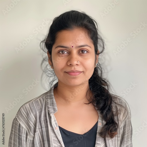 Portrait of an Indian woman standing near a wall with grey background