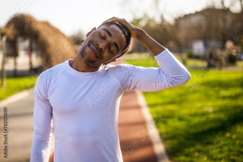 Young african-american man is exercising in the city. He is stretching his body.