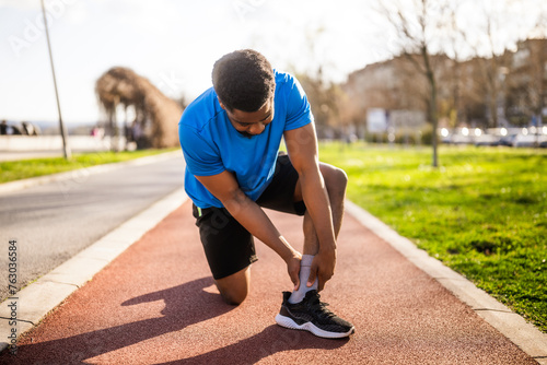 Young african-american man is injured while jogging. He twisted his ankle.