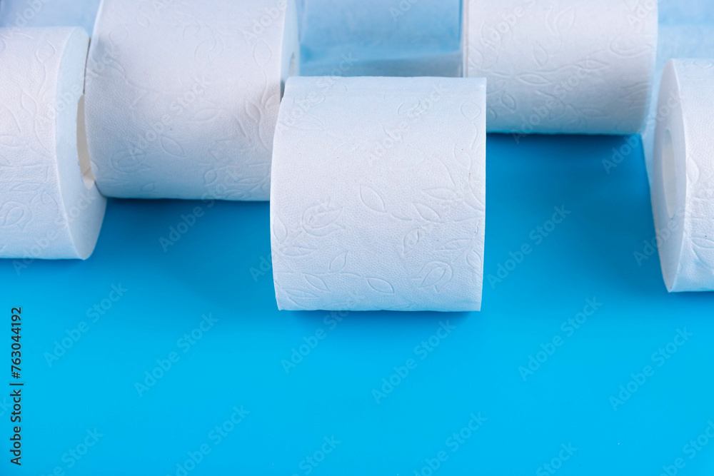 Obraz premium Rolls of white toilet paper on a blue background with place for text, advertising.