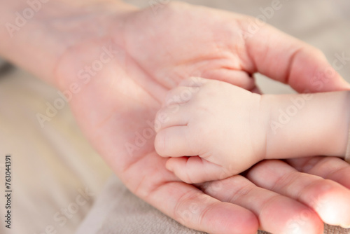 Hand with fingers of a newborn baby and mom's hand.