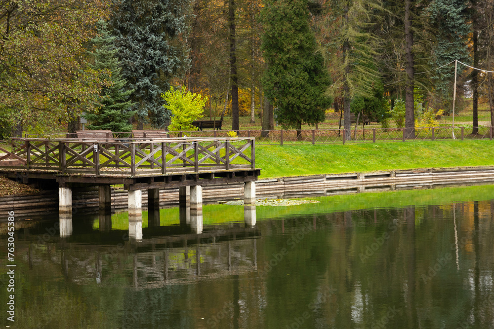 The wooden bridge with a viewing platform and benches over the lake. The wooden bridge with a viewing platform and benches over the lake.