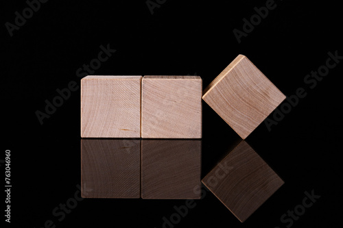 Three wooden cubes, blocks with empty space for copying words, messages, lie on a black reflective background. Business idea.
