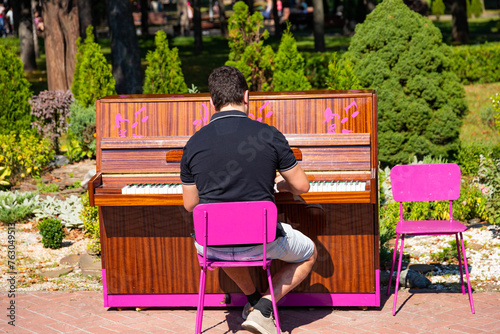 A man plays the piano on the street in the park. Street musician plays classical music on the piano in the park on a sunny day. photo