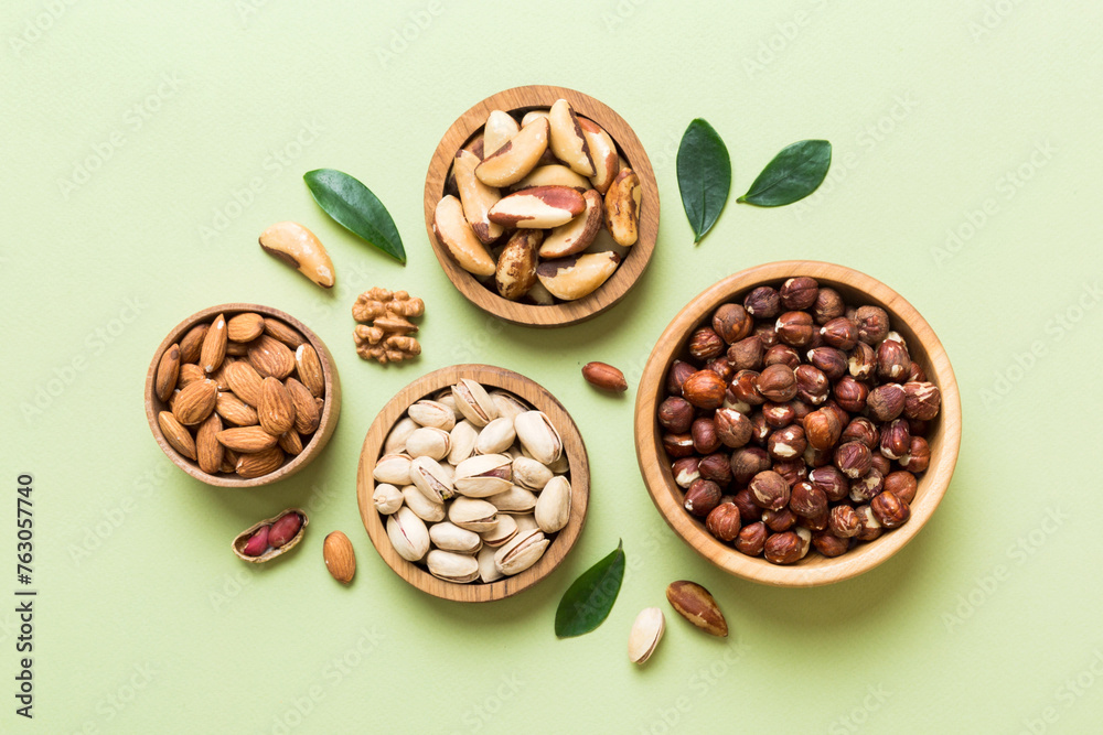 mixed nuts in wooden bowl. Mix of various nuts on colored background. pistachios, cashews, walnuts, hazelnuts, peanuts and brazil nuts