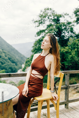 Portrait of a young brunette in a brown dress. sexy girl posing on the veranda in nature