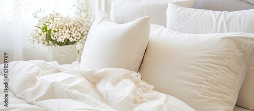 A comfortable room with a bed adorned in white linens and pillows, with a vase of flowers in the background, creating a peaceful and inviting atmosphere