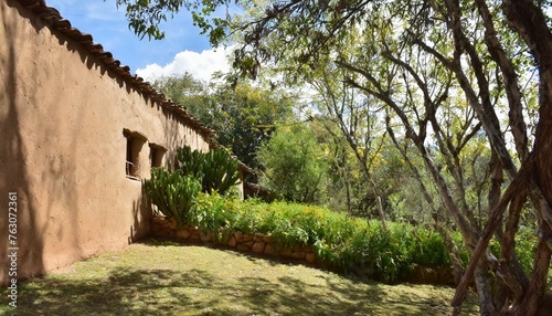 Adobe house wall with a garden full of trees behind it