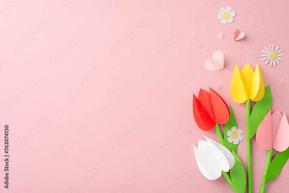 Personalized Mother's Day greeting. Top view image of hand-folded tulips, chamomiles, and love symbols amid fine confetti on muted pink setting, earmarking area for personalized text or commercial use Personalized Mother's Day greeting. Top view image of hand-folded tulips, chamomiles, and love symbols amid fine confetti on muted pink setting, earmarking area for personalized text or commercial use
