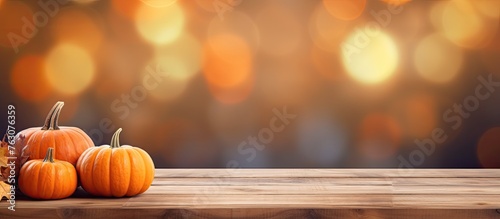 Three pumpkins, in shades of orange and calabaza, rest on a wooden table. These natural foods belong to the plant family and are classified as winter squash vegetables photo