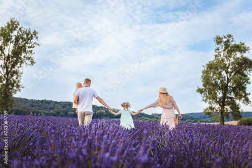a family walks on a lavender field. father and mother with two daughters