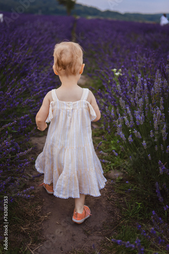 It's a beautiful day and a little girl is walking through a field of lavender