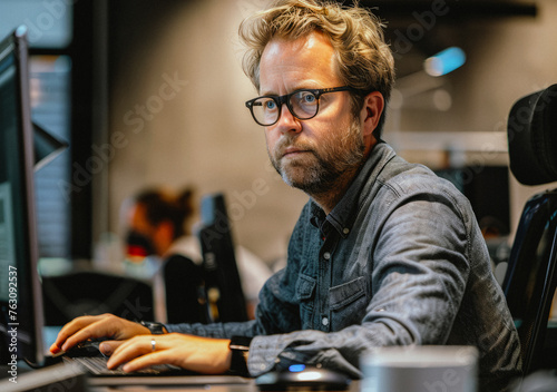 Man sits at desk and works on computer.