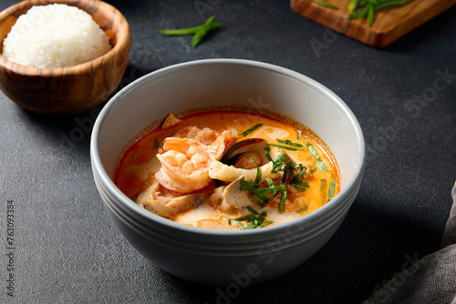 Tom Yum seafood soup with shrimp and mussels, front view on a dark slate