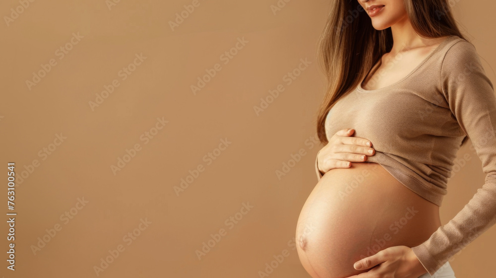 Young pregnant woman on beige background. Waiting for the birth of a child Young pregnant woman on beige background. Waiting for the birth of a child