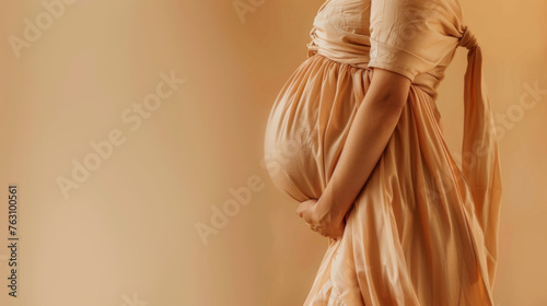 Young pregnant woman on beige background. Waiting for the birth of a child
