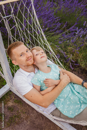 father and daughter lie in a hammock. lavender field in the background