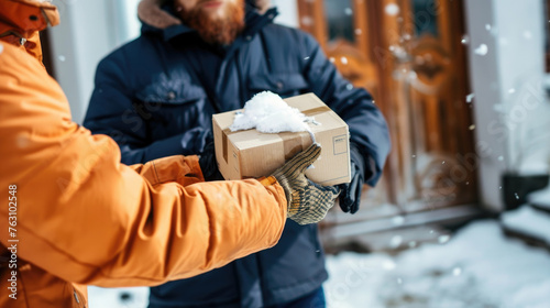 A person in a warm orange jacket hands a package to a recipient on a cold, snowy day