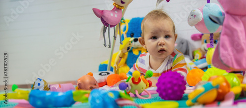 a child plays with hanging toys on a play mat. the child plays with toys at home.