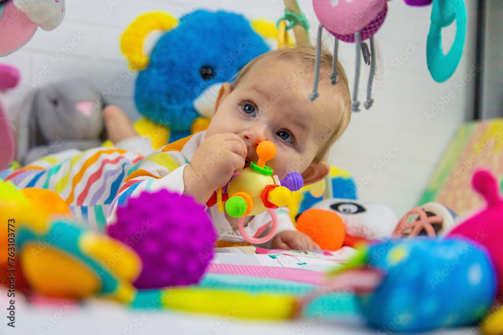 a child plays with hanging toys on a play mat. the child plays with toys at home. a child plays with hanging toys on a play mat. the child plays with toys at home.