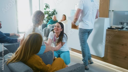 Friendly female doctor or pediatrician is talking to a little girl patient in the waiting room of a medical clinic or hospital. Waiting room in modern medical center. Healthcare system. photo