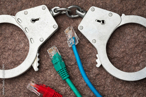 Top view of handcuffs and computer wires, concept on the theme of punishment in the field of computer crimes