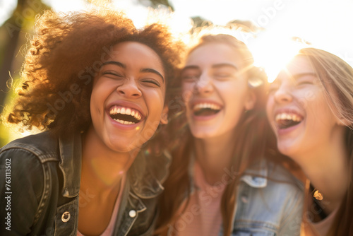 Close-Up Joyful Women Enjoying Golden Hour. Group of young women laughing together outdoors in sunlight, ideal for themes of friendship and joy.