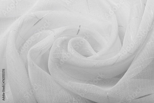 White tulle fabric rolled into a rose. The folds of the curtain are waves of a flower bud.