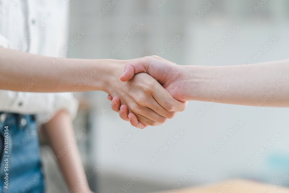 Close-up of a warm, friendly handshake between two professionals in a bright, casual setting, signaling a positive agreement. Close-up of a warm, friendly handshake between two professionals in a bright, casual setting, signaling a positive agreement.