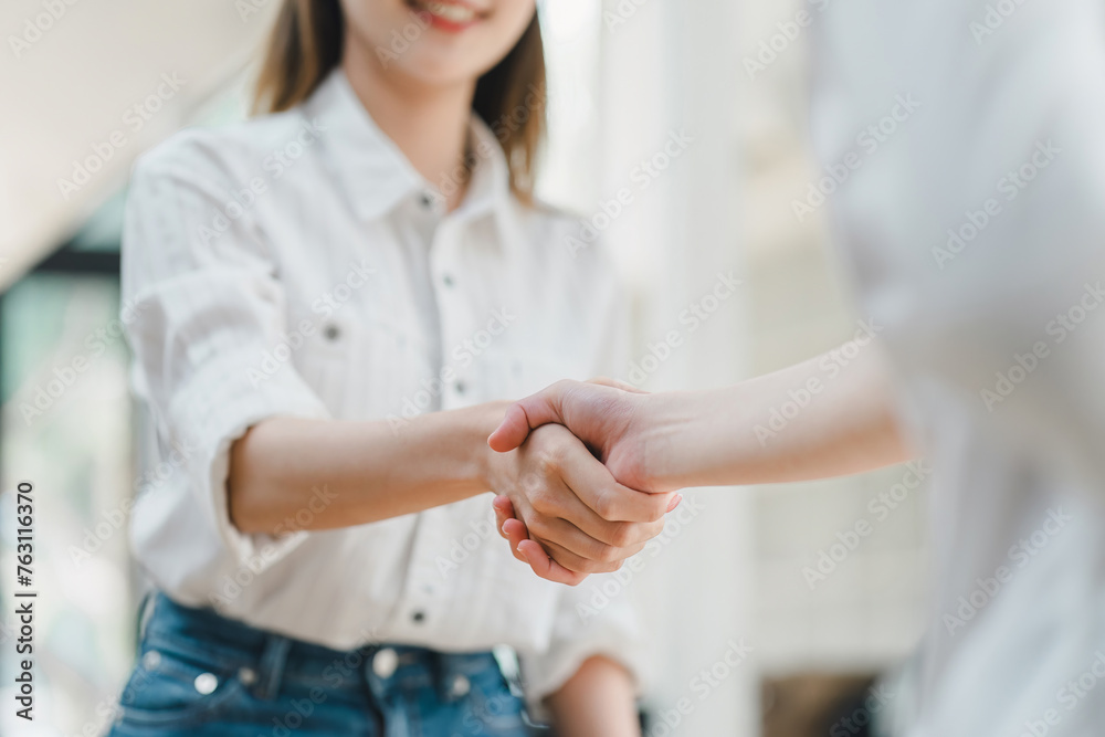 Close-up of a warm, friendly handshake between two professionals in a bright, casual setting, signaling a positive agreement. Close-up of a warm, friendly handshake between two professionals in a bright, casual setting, signaling a positive agreement.