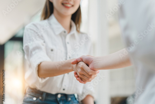 Close-up of a warm, friendly handshake between two professionals in a bright, casual setting, signaling a positive agreement.