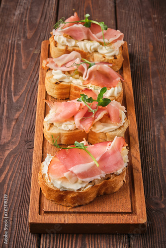 gourmet ham and cream cheese canapés on wooden board