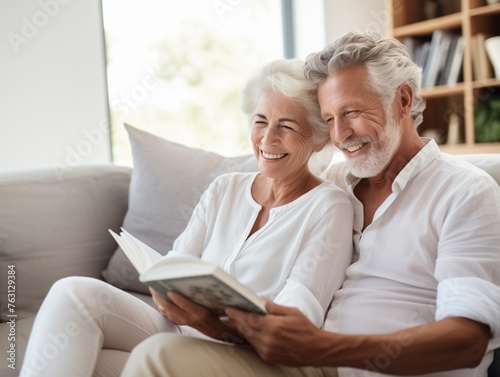 photo of older couple looking at a photo album or book on the couch, relaxed and smiling