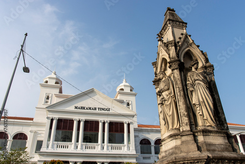 Neo gothic memorial statue and the Supreme Court Building (Malaysian: Mahkamah Tinggi)at Light Street (Lebuh Light) in the historic district of George Town, Penang, Malaysia, Asia photo