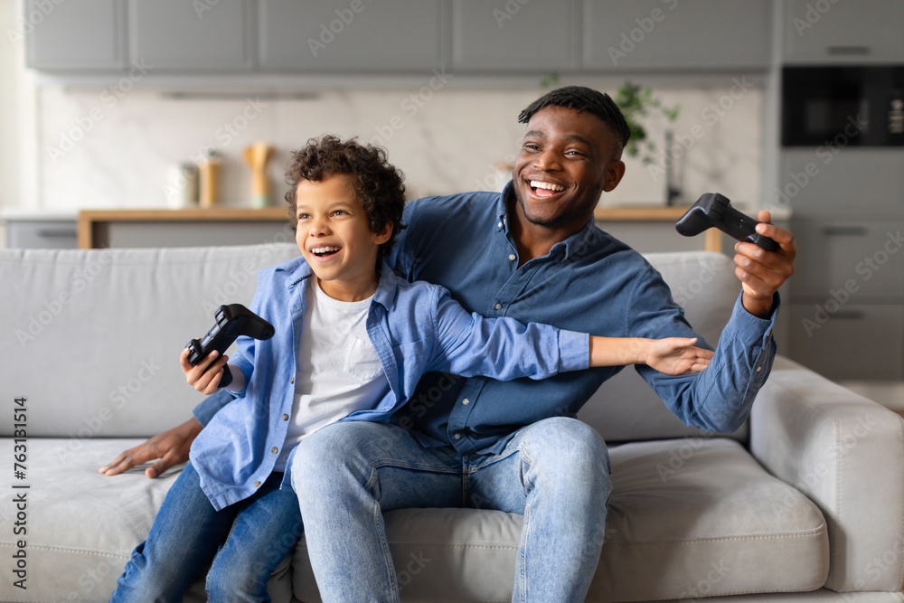 Father and son playing video games and laughing Father and son playing video games and laughing