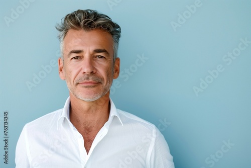 Portrait of a confident middle-aged man in white shirt against a blue background looking at camera with text space. © Generative ART