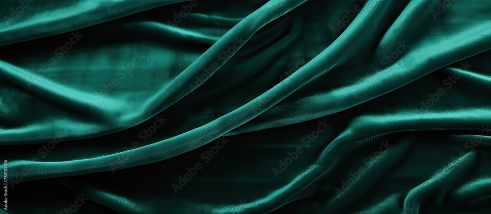 Obraz premium A closeup shot of a piece of dark green velvet fabric with a vibrant electric blue pattern resembling aquatic plants. The texture is liquidlike and mesmerizing
