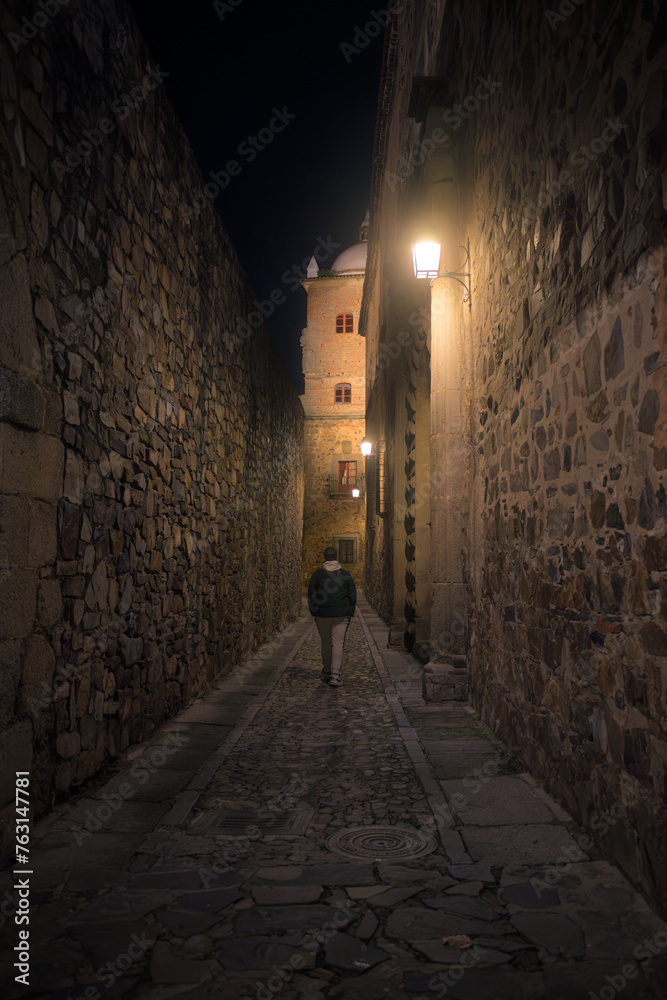 Man walking down dark alleyway in Caceres, Spain
