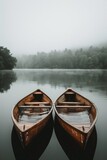 Two wooden row boats in the middle of a lake, with a foggy forest mountain background, shot in the style