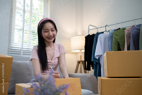 Young start up online business SME beautiful woman female Asian working writing on box for prepare shipping product to customer, Shipping shopping online, SMW working with box at home photo