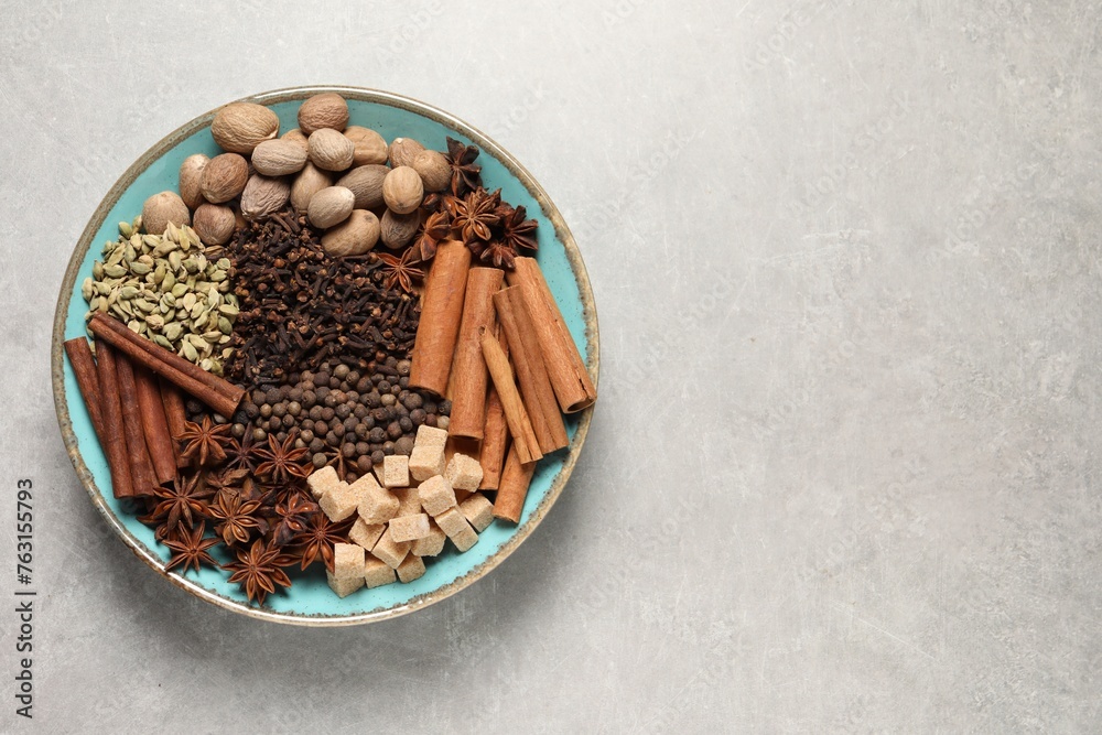 Different spices and nuts in bowl on light gray textured table, top view. Space for text Different spices and nuts in bowl on light gray textured table, top view. Space for text
