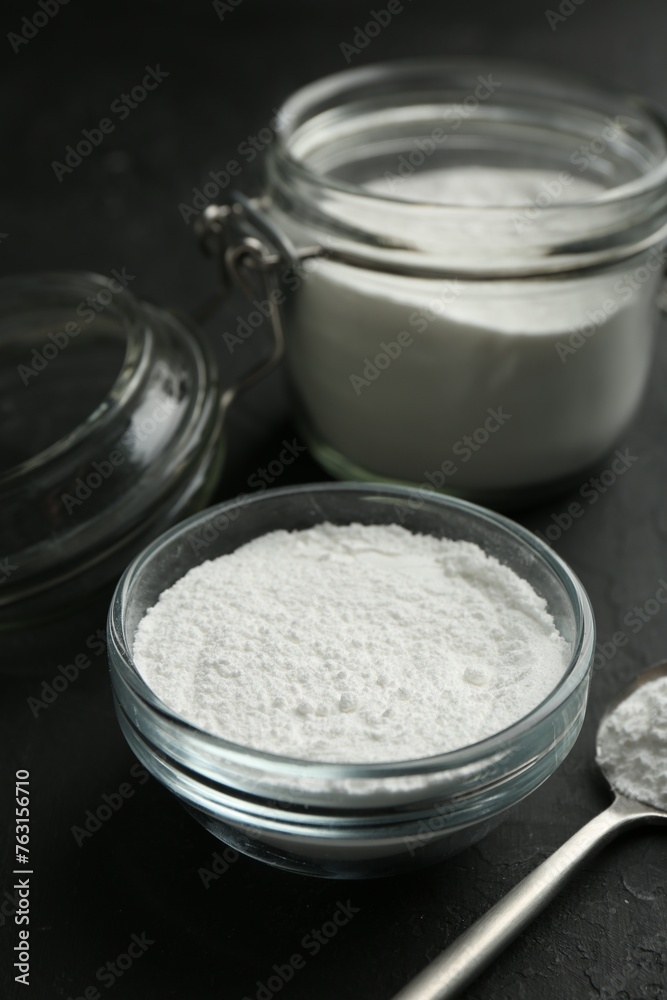 Baking powder in bowl, jar and spoon on black textured table, closeup Baking powder in bowl, jar and spoon on black textured table, closeup
