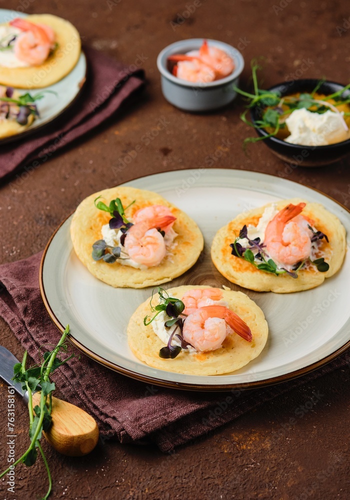 Pancakes with cream cheese, microseneous and shrimp on a ceramic plate on a brown concrete background. Pancakes recipes, snacks. International Pancake Day. Pancakes with cream cheese, microseneous and shrimp on a ceramic plate on a brown concrete background. Pancakes recipes, snacks. International Pancake Day.