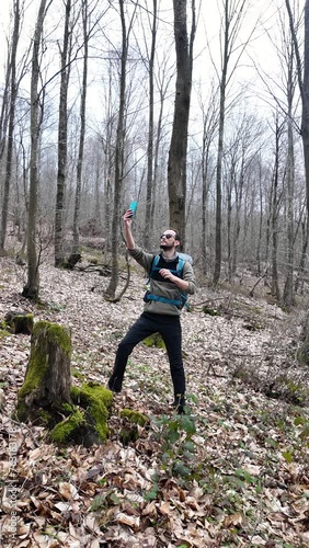 Solo camper in a campsite tries to catch a cell signal on the phone in the forest, no signal on the phone. Vertical.