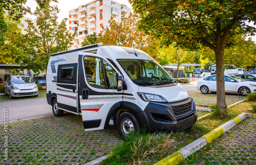 Camper van or motor home is parked in residential parking place in front of apartment building. Motorhome parked in public parking in Mostar, Bosnia. Campervan and city parking.