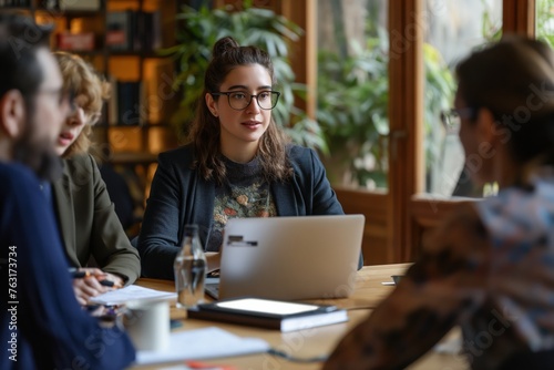 Casual business discussion in cozy office. Woman in glasses discussing work with colleagues in a casual office setting