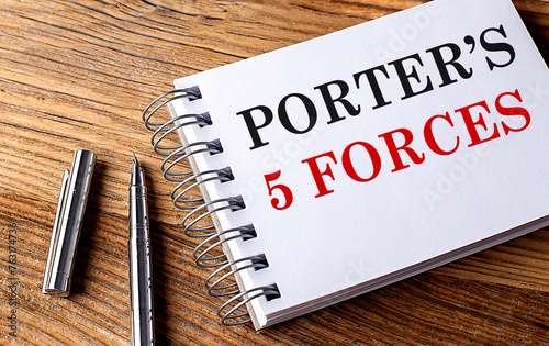 PORTER'S 5 FORCES text on notebook with pen on the wooden background