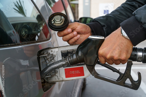 Hands of a man filling up a car with gasoline at a gas station photo