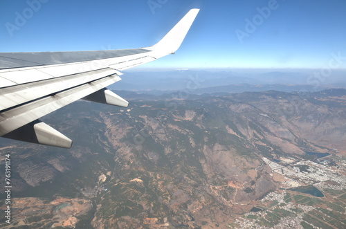 plane wing and mountain background on sky through window frame