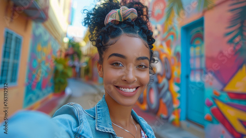 A smiling woman taking a selfie with street art.